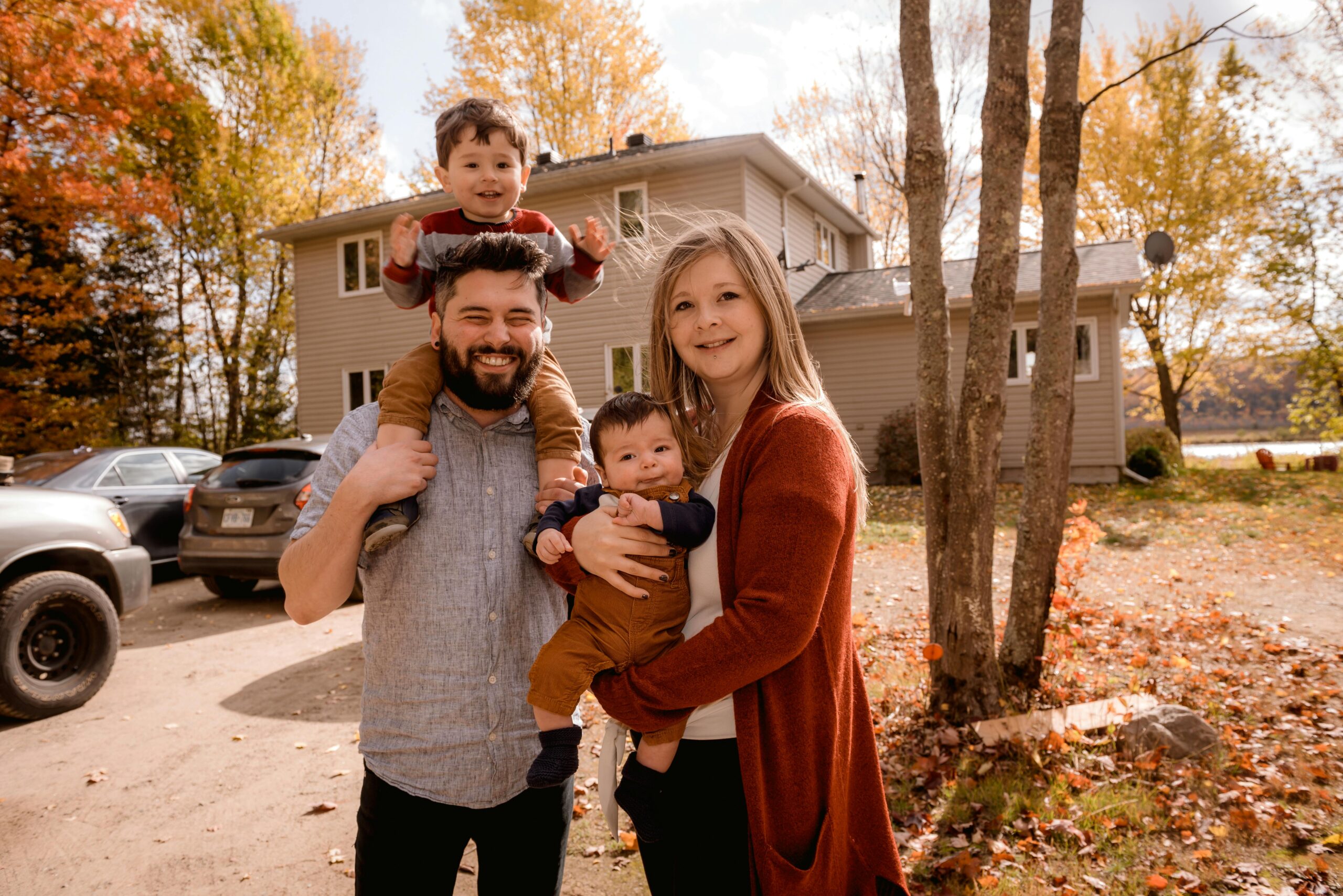 Smiling family of four posing outside their house in autumn.