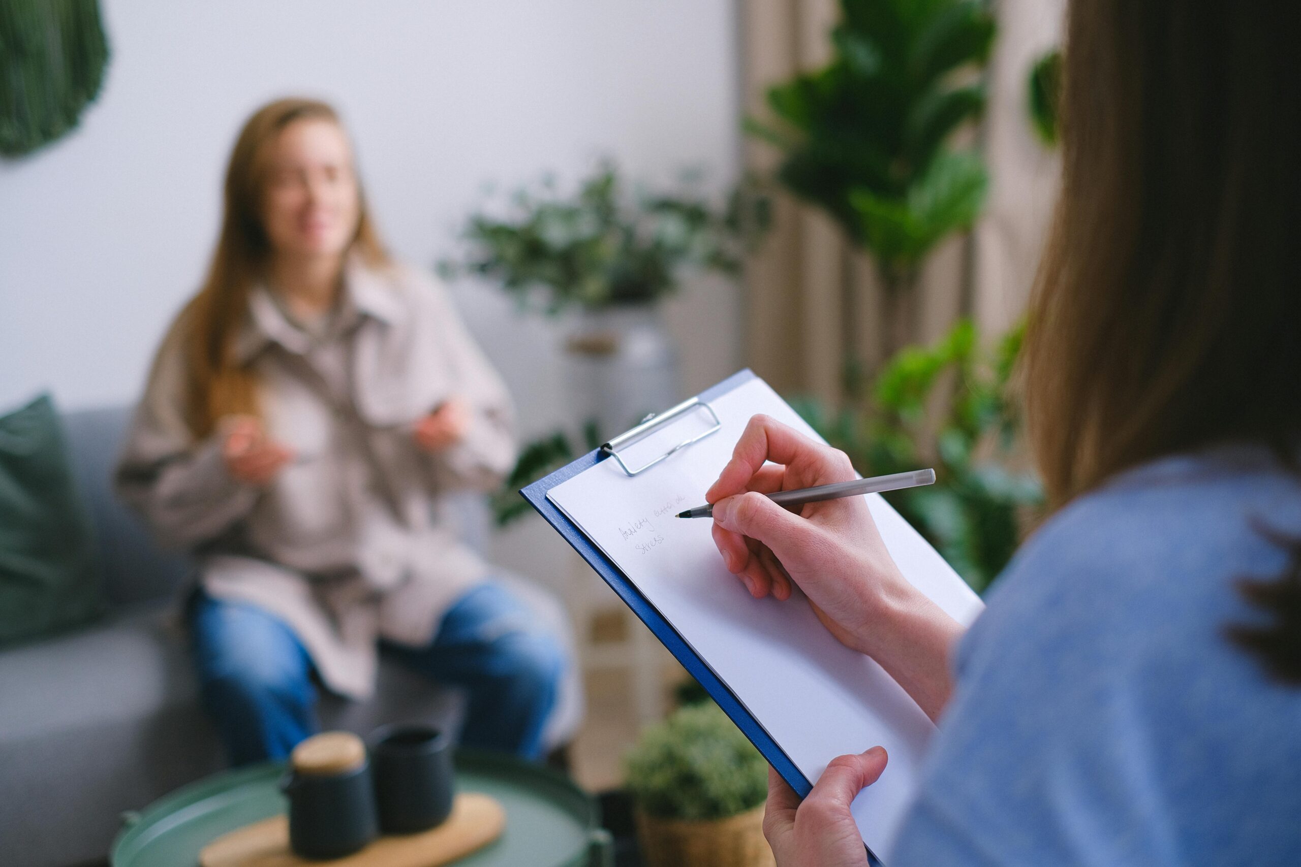 Therapist taking notes while woman talks during a counseling session.